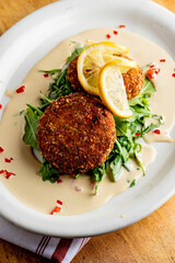 Crab cake. Crab cake served with spicy rémoulade sauce on top of a mixed green salad. Jumbo crab meat mixed with garlic, onions, spices and fried in butter. Classic American restaurant appetizer.