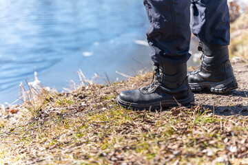 Legs of a tourist in boots on the river bank
