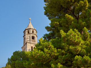 Fototapeta na wymiar Tower of the Church and Monastery of Our Lady of the Snow with a big tree in the forefront. Cavtat, Croatia, Europe