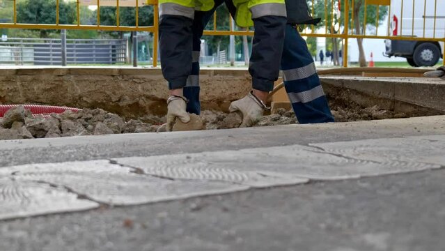workman picks up stones in a city road repair