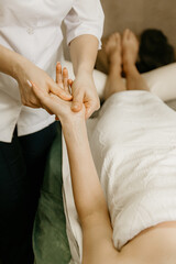 Professional manual therapist makes the hands of a young woman. Treatment of muscles and joints of the hands.