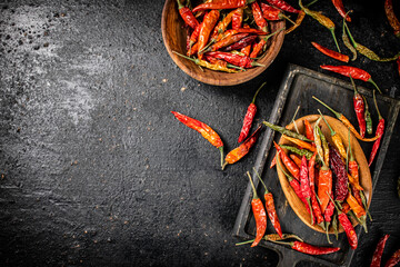 Multicolored pods of dried chili peppers on a cutting board. 