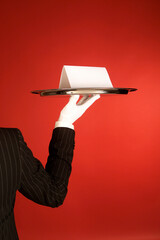 Hand of waiter in suit holding tray with blank card with space for text, service concept