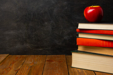 Back to school. Education background with books and apple over blackboard