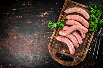 Raw sausages on a cutting board with parsley. 
