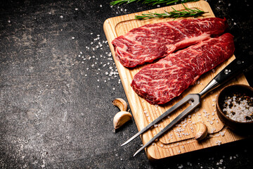 Raw steak on a wooden cutting board. 