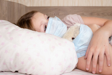 Unhealthy little girl child sleep in bed relax at home in bedroom. Sick ill little kid suffer from flu fever asleep in bed on lockdown quarantine. the child lies in bed in a medical mask