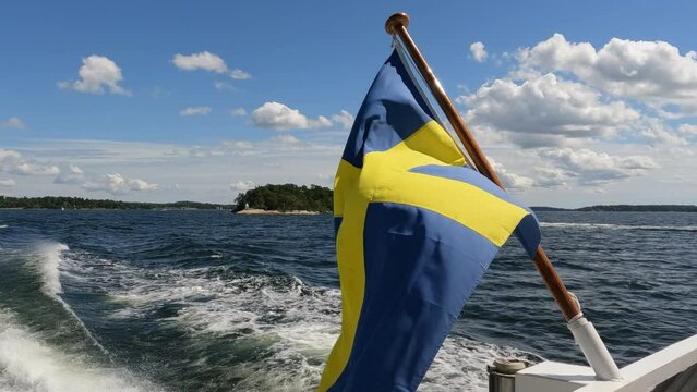 Swedish flag waving on rear of boat underway in Stockholm Archipelago. Close up video of flag on right side