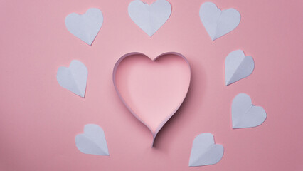 Composition for Valentine's Day February 14th. Delicate pink background and pink hearts cut out of paper.
