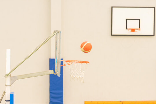 side view of basketball entering a mini-basketball basket