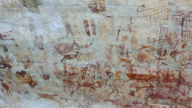 Aerial frontal drone shot of a large wall covered in ancient rock painting in a jungle environment in the interior of Colombia 4K
