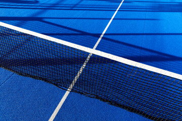 Tennis court. The sports field is bright blue with white stripes and a black net. Composition of geometric patterns and lines.