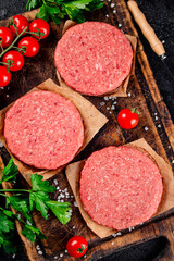 A raw burger on a tomato cutting board. 