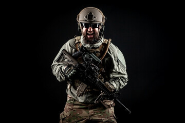 angry soldier in uniform with a rifle screaming at night, commando in stress on a dark background,...