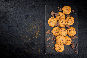 Cookies with pieces of milk chocolate on a stone board. 