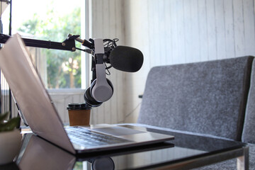 Home studio podcast setting. Microphone, laptop and headphones on the table.