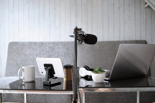 Home studio podcast setting. Microphone, laptop and headphones on the table.