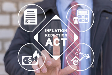 Businessman using virtual touchscreen presses the inscription: INFLATION REDUCTION ACT. Concept of...