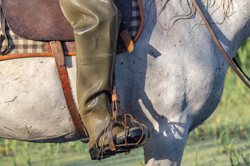 Rubber waders on a horse rider in the marshes of the Camargue. - obrazy, fototapety, plakaty