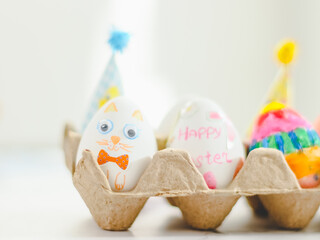 Cardboard package with decorated Easter eggs with glued and painted Easter bunny faces on a marble table