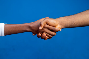 Business agreement handshake over a blue studio background