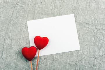 Blank card, two red toy hearts on a grey textile background. Valentines day concept. Top view, flat lay, mockup