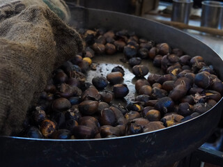 Big hot pan of roasted chestnuts with smoke ,italian street food