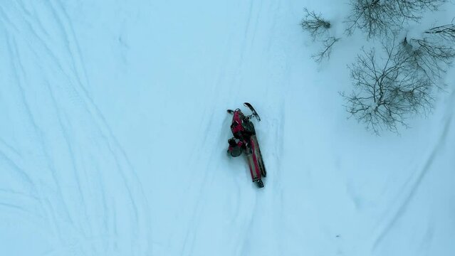 Aerial drone view on man drifts in circles on a snowmobile in the snowy winter mountains. Snowmobilers sports riding. High quality 4k footage
