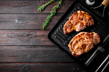 Cooked pork steak in a frying pan grilled with rosemary. 