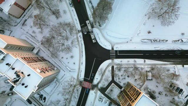 Flight above the winter snowy crossroads in Krakow at sunset. Aerial view of the residential district, cars and yards covered with snow.