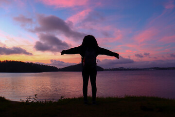 girl with open arms looking at the sky in front of the sea
