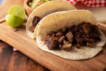Tacos de Bistec. Homemade grilled meat in a corn tortilla. Street food from Mexico, traditionally accompanied with cilantro, onion and spicy sauce or guacamole