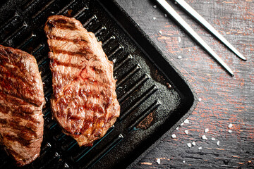 Aromatic grilled steak in a frying pan. 