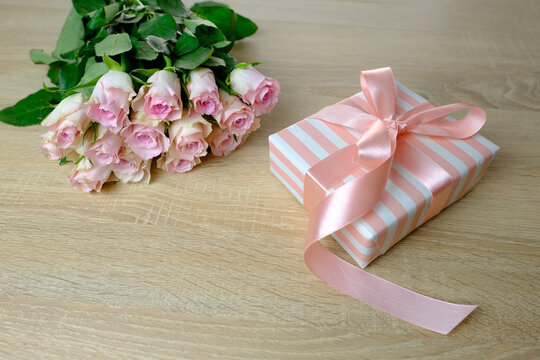 bouquet of white, pink roses, box with gift with satin ribbon, flowers for professional holiday on light table in office, concept of mother's, Valentine's day, birthday, selective focus