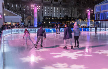 People skating on an outdoor rink in Bryant Park, New York City, at night