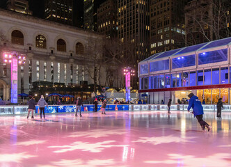 People skating on an outdoor rink in Bryant Park, New York City, at night