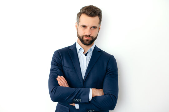 Photo of a handsome serious caucasian successful business man in a suit, seo, banker, broker, financial director, standing on isolated white background with arms crossed, looking at camera