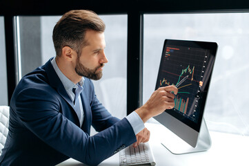 Thoughtful focused clever successful caucasian male stock investor, broker, sits at his work desk,...