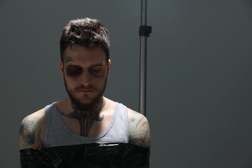 Man with bruise taped up and taken hostage on grey background. Space for text
