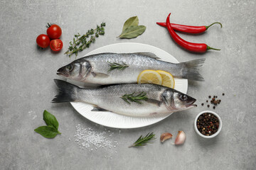 Sea bass fish and ingredients on grey table, flat lay