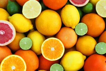 Many different whole and cut citrus fruits as background, top view