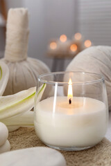 Spa composition with burning candle and herbal bags on massage table in wellness center