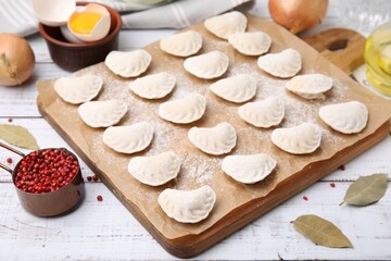 Raw dumplings (varenyky) with tasty filling and ingredients on white wooden table