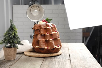 Professional equipment and Christmas composition with Pandoro cake on wooden table in studio. Food photography
