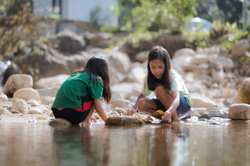 Two asian siblings playing sand nearing the river together with fun. Outdoor activity for children on vacation.