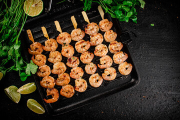 Grilled shrimp in a frying pan with parsley and pieces of lime. 