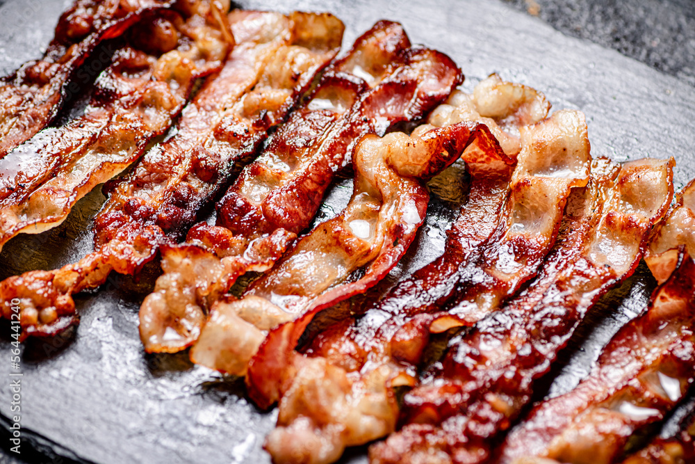 Poster Strips of fried bacon on a black background.