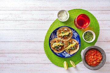 Mexican tacos served on green napkin, top view of taco served on blue ceramic plate near bowls of...