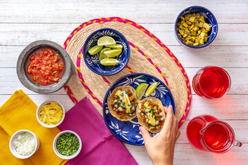 Crop person putting tomato sauce on mexican tacos, top view of crop anonymous person adding salsa...