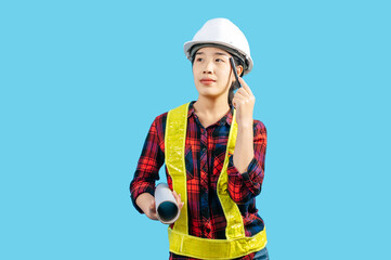 Young asian engineer female wearing safety jacket and helmet hold blue print